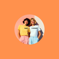 Two women wearing casual women’s clothing, smiling and standing together against an orange background